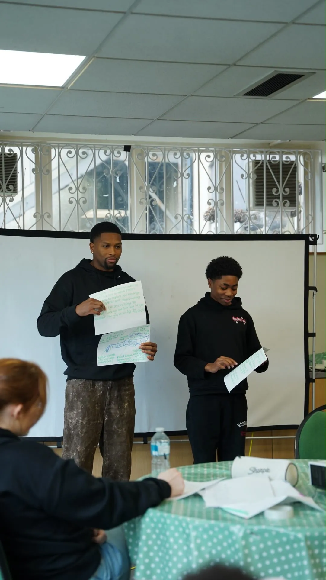 A young person and a Care Cove staff member presenting a design drawn on paper