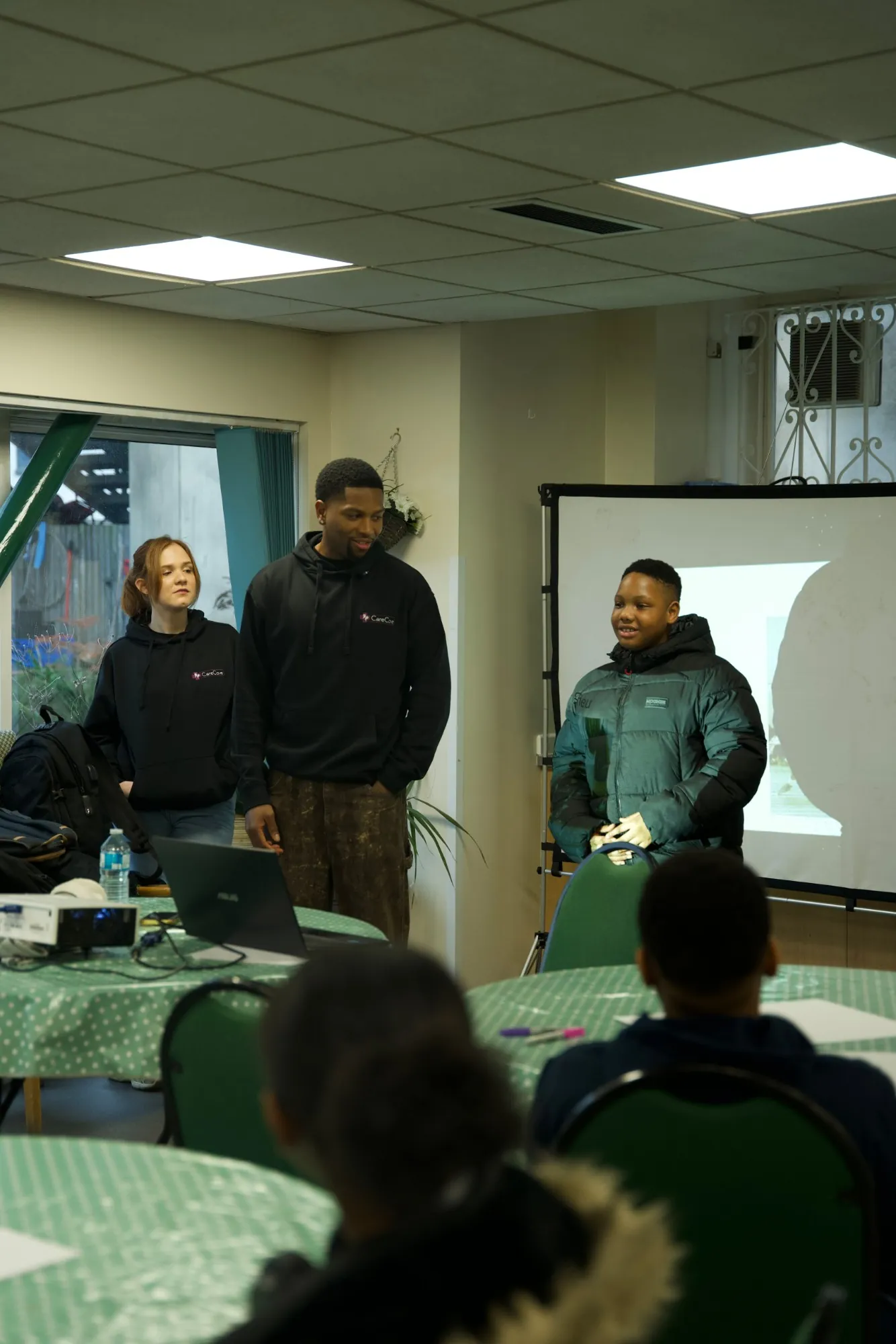 A young person speaking to the group, standing beside two Care Cove staff members